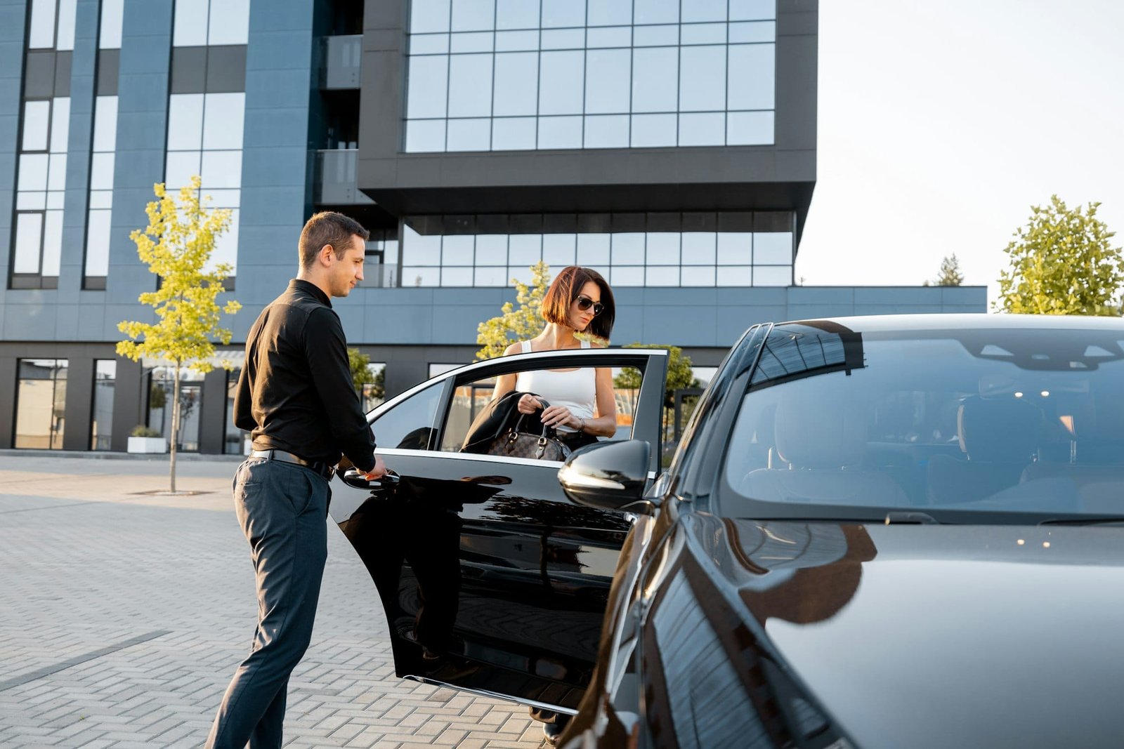 Chauffeur helps an elegant business woman gets in car